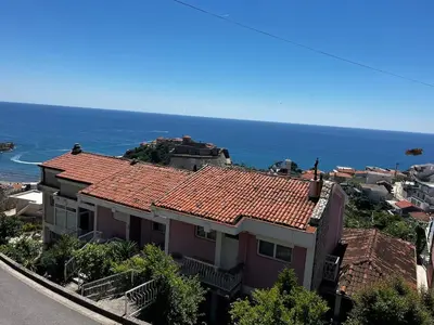 a house with a red roof with the ocean in the background at Vaidas place in Ulcinj