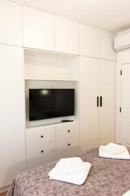 a white bedroom with a tv and white cabinets at Konzul apartment in Kotor