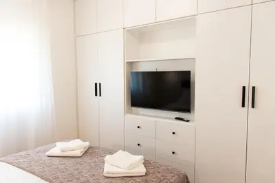 a white bedroom with a tv and white cabinets at Konzul apartment in Kotor