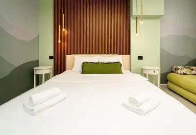 a bedroom with a large white bed with two towels at 7 Hills Rooms in Podgorica