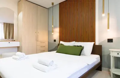 a bedroom with a large white bed with green accents at 7 Hills Rooms in Podgorica