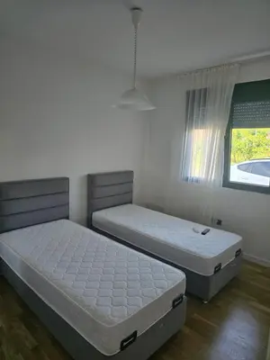 two twin beds in a room with a window at Lux apartment in Podgorica