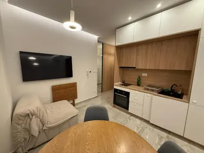 a living room with a table and a tv on the wall at Aura Tower in Rafailovici