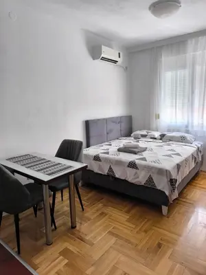 a bedroom with a bed and a table and chairs at Apartment 365 in Podgorica