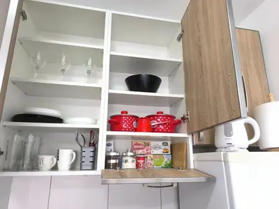 a kitchen with white cabinets and red dishes at Apartment 365 in Podgorica