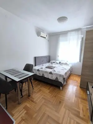 a bedroom with a bed and a table in it at Apartment 365 in Podgorica