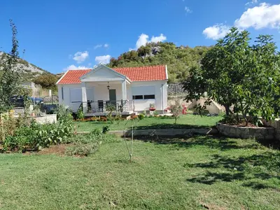 a small white house with a tree in a yard at Eco-Apartment Ostros Skutarisee