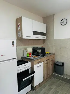 a kitchen with white appliances and a clock on the wall at Uros Apartments in Tivat
