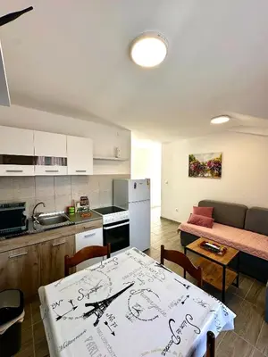 a kitchen and a living room with a table and a couch at Uros Apartments in Tivat