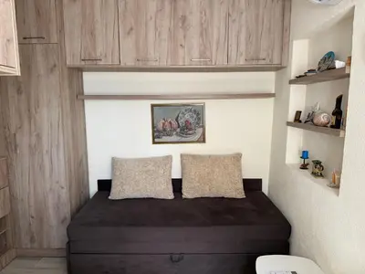 a small bedroom with a bed and wooden cabinets at Private double room in the Old Town in Budva