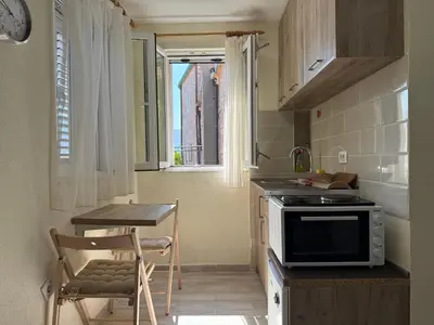 a small kitchen with a stove and a table at Private double room in the Old Town in Budva