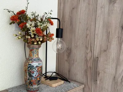 a vase with flowers on a table with a lamp at Private double room in the Old Town in Budva
