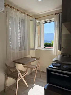 a table and a chair in a kitchen with a window at Private double room in the Old Town in Budva