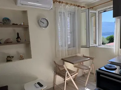 a kitchen with a table and a clock on the wall at Private double room in the Old Town in Budva