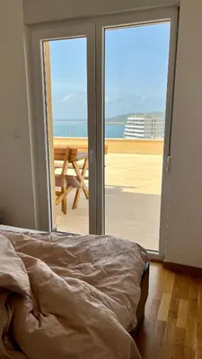 a bedroom with a bed and a view of the ocean at Penthouse Becici in Budva