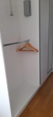 a refrigerator in a white room with a wooden hanger at Penthouse Becici in Budva