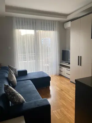 a living room with a blue couch and a television at Montesin cozy studio in Budva