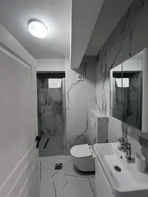 a white bathroom with a toilet and a sink at Apartment AB in Bar