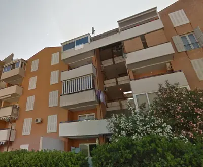 an apartment building with balconies and trees at Fighen Apartment in Budva