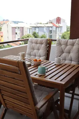 a wooden table and chairs with a bowl of fruit on it at Fighen Apartment in Budva
