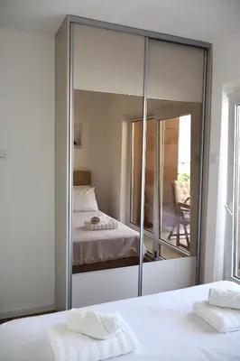 a mirror in a bedroom with a bed and a chair at Fighen Apartment in Budva