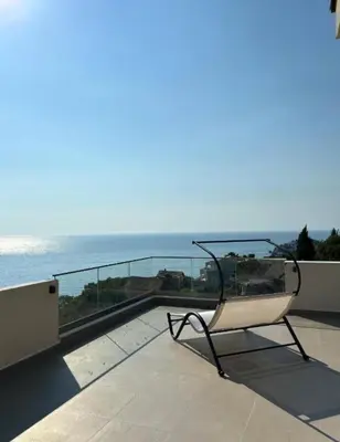 a chair sitting on a balcony overlooking the ocean at B&K Villa Kruče Rooms in Ulcinj