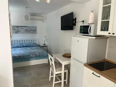 a small room with a bed and a desk and a kitchen at Cozy Kotor apartment in Dobrota