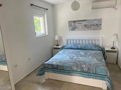 a white bedroom with a bed and two windows at Cozy Kotor apartment in Dobrota