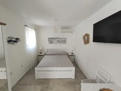 a white bedroom with a bed and a flat screen tv at Cozy Kotor apartment in Dobrota