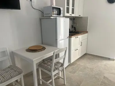 a small kitchen with a table and a white refrigerator at Cozy Kotor apartment in Dobrota