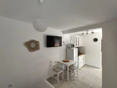 a kitchen with a small table and a white refrigerator at Cozy Kotor apartment in Dobrota