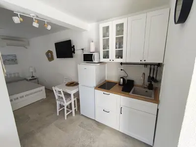 a small kitchen with white cabinets and a small table at Cozy Kotor apartment in Dobrota