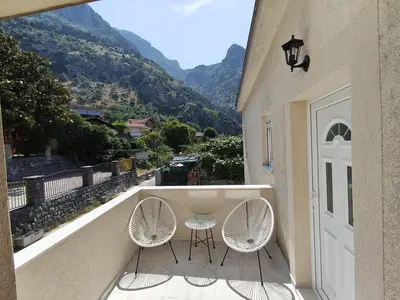 two chairs and a table on a balcony with mountains at Cozy Kotor apartment in Dobrota