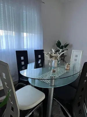 a glass table with chairs and a vase of flowers on it at Studio Apartmani Delić