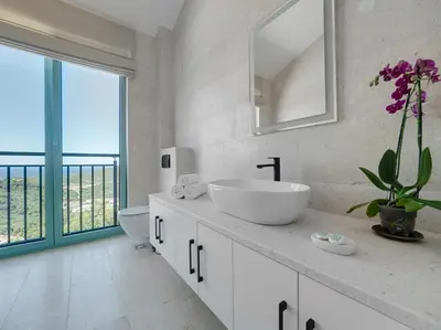 a white bathroom with a sink and a mirror at Villa Zvis Sea View with Private Pool & Peaceful Stay in Budva