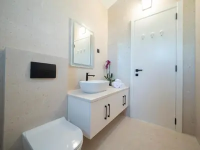 a white bathroom with a sink and a toilet at Villa Zvis Sea View with Private Pool & Peaceful Stay in Budva
