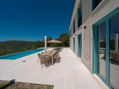 a patio with tables and chairs next to a building at Villa Zvis Sea View with Private Pool & Peaceful Stay in Budva