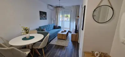 a living room with a table and a blue couch at kotor apartman 3 in Kravlja