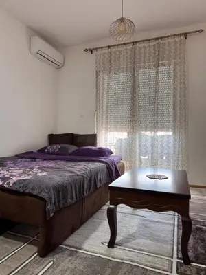 a bedroom with a bed and a table and a window at Stan na dan, Stari aerodrom! in Podgorica