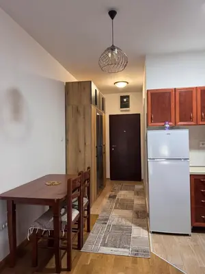 a kitchen with a table and a white refrigerator at Stan na dan, Stari aerodrom! in Podgorica