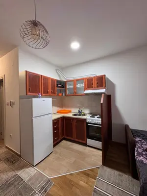 a kitchen with a white refrigerator and wooden cabinets at Stan na dan, Stari aerodrom! in Podgorica
