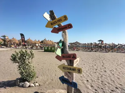 a wooden sign on the beach with direction signs at Montenegro Ulcinj Apartments in Kravlja