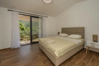 a bedroom with a large bed and a balcony at Forest Nest Bartula in Bar