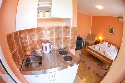 a small kitchen with a sink and a living room at Lidia Apartments in Budva