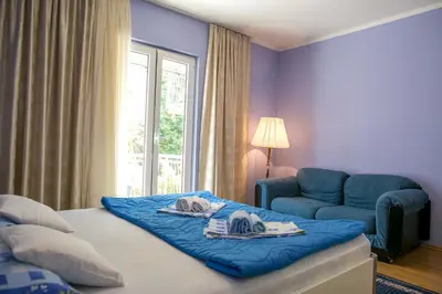 a bedroom with a bed and a chair and a window at Lidia Apartments in Budva