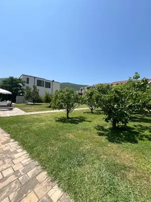 a grassy yard with trees and a building at Sunny Apart in Budva