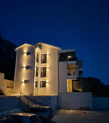 a white building with a car parked in front of it at ZEN Studio Apartman in Kotor