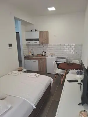 a room with a bed and a table and a kitchen at ZEN Studio Apartman in Kotor