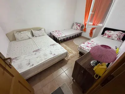 a room with two beds and a chair and a table at Apartman Adea in Donji Štoj