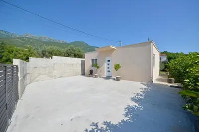 a white house with a large concrete driveway at Holiday Home Stanka in Kotor
